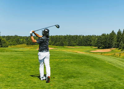 A golfer teeing off on a lush green course at Rodd Brudenell River near crowbush golf resort
