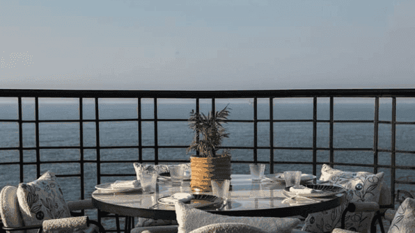 طاولة طعام في الهواء الطلق مع إطلالة على البحر في مطعم Em Sherif في بيروت في فندق Warwick Palm Beach - بيروت.