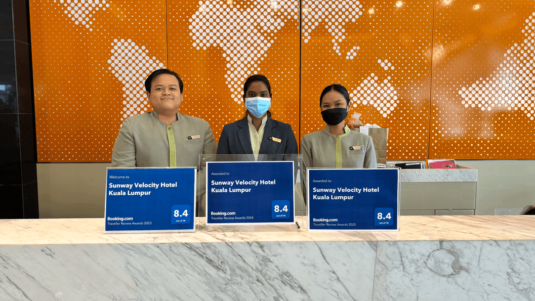 Hotel staff proudly holding up three Booking.com Traveller Review Awards for 2023, 2024, and 2025 at Sunway Velocity Hotel