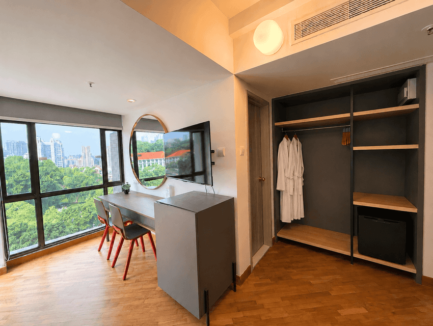 Workspace corner with TV and open wardrobe in Parkview Serviced Suite for an extended stay at YWCA Fort Canning