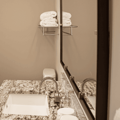Granite countertop vanity with stainless steel faucet under large framed wall mirror at La Tourelle Hotel and Spa