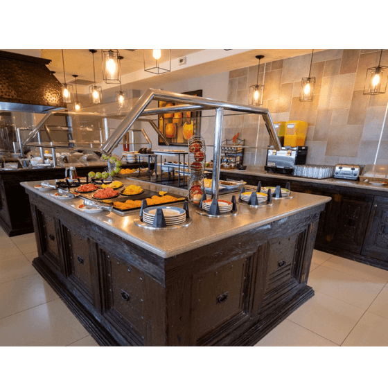 Breakfast buffet station with fresh sliced fruit and toaster appliances inside Cafeteria Palmira at Araiza Calafia