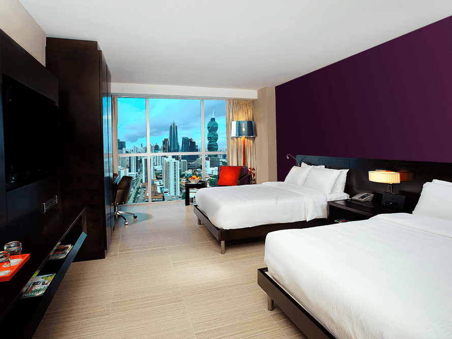 Cómoda cama con área de TV en Doble Deluxe Vista a la Ciudad en Megapolis Hotel Panamá