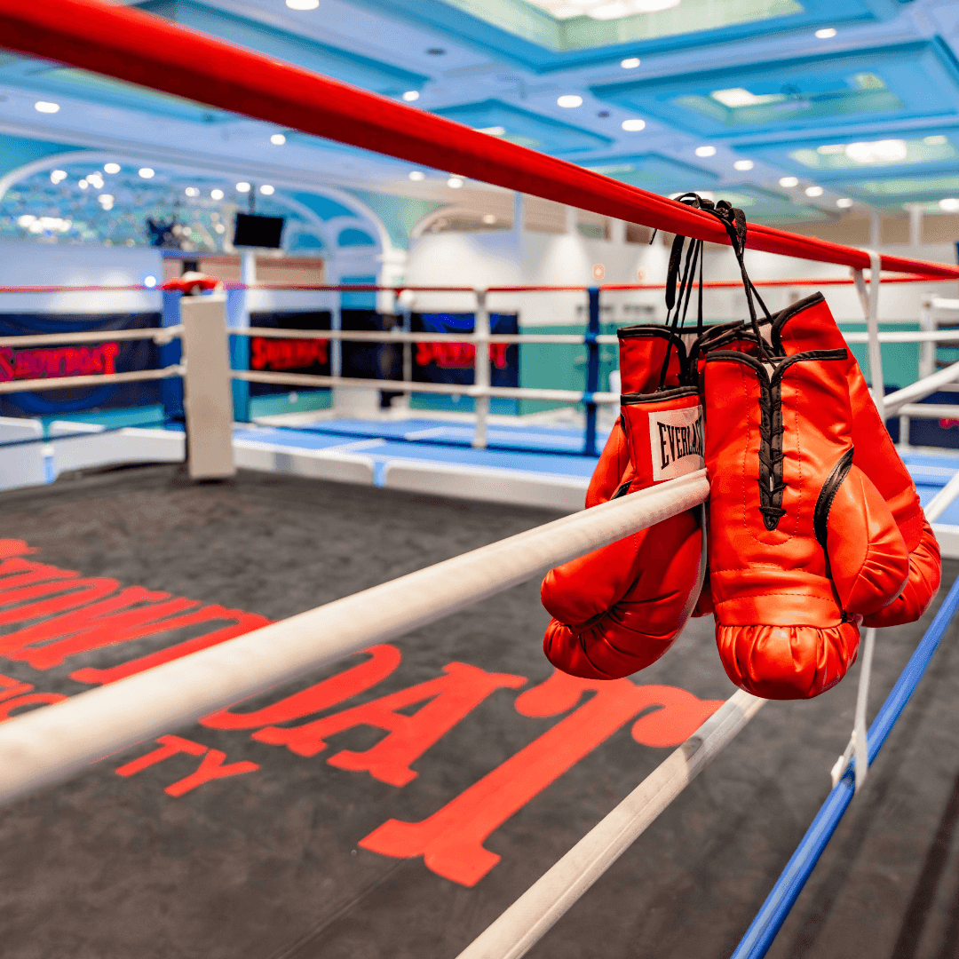 Red boxing gloves hanging on the ropes of a boxing ring at Showboat Hotel & Resort