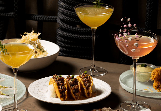 Crispy tacos and cocktails served on a table at The Londoner