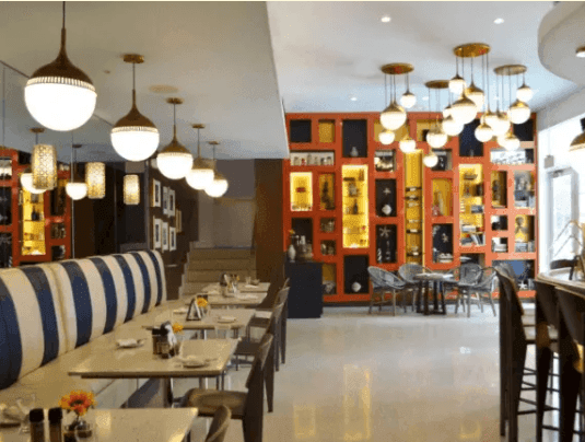 The Tavern dining area at Riviera Hotel South Beach with striped booths, white tables, and distinctive globe pendant lights