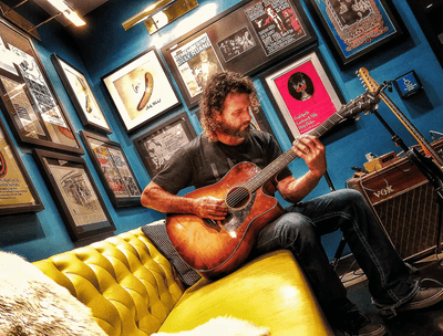 Man playing the acoustic guitar in lobby lounge area at The Verb Hotel