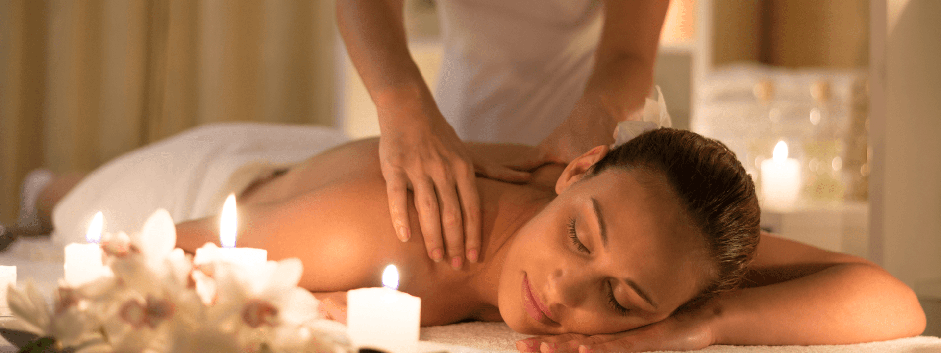 Person receiving a back massage in a serene setting with candles at Polonia Palace Hotel
