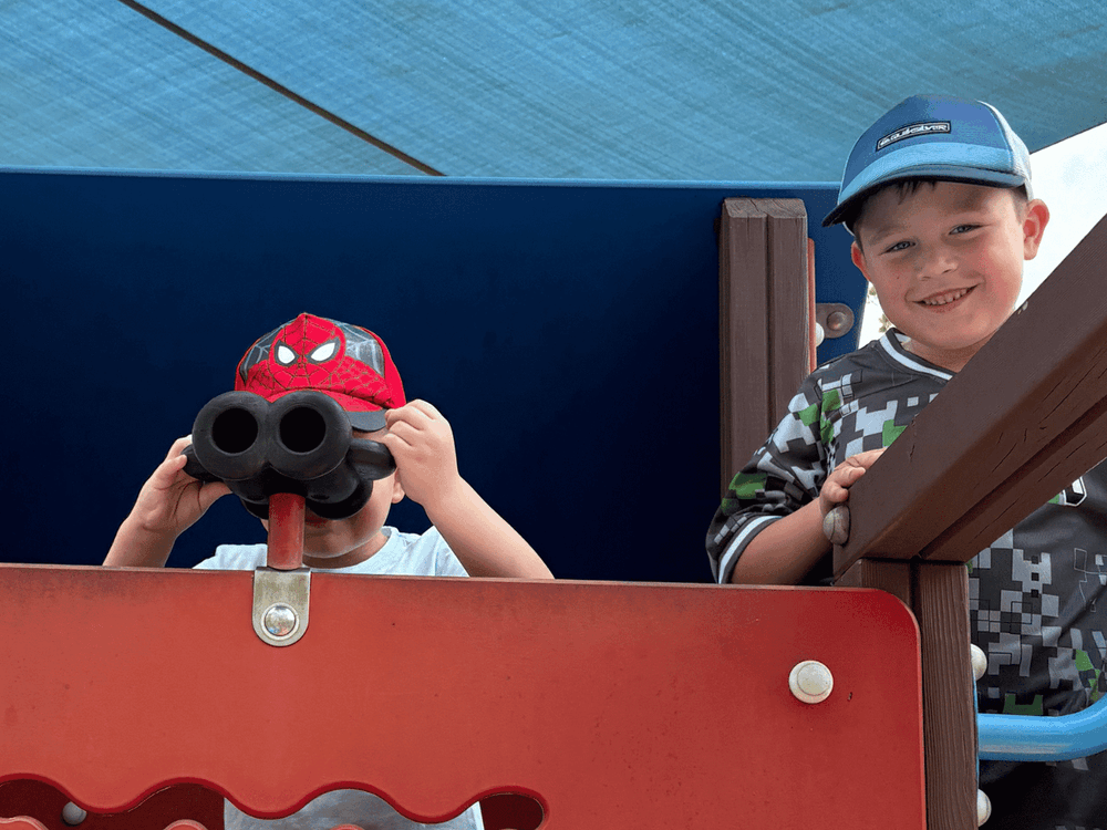 Two boys on a play structure with binoculars at Winter School Holidays Activities.