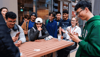 Group of students playing cards and socializing around an outdoor table at UniLodge student accommodation