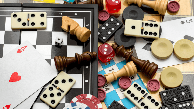 Game pieces, cards, and dominoes are scattered on a game board.