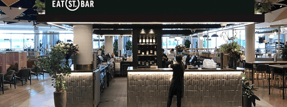 Modern, inviting Eat St. Bar at Novotel Sydney, with a bartender preparing drinks in a lively social setting