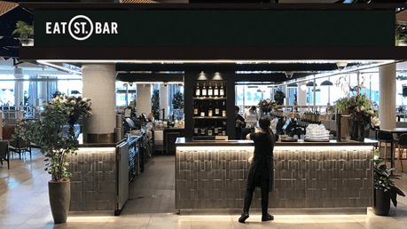 Modern, inviting Eat St. Bar at Novotel Sydney, with a bartender preparing drinks in a lively social setting