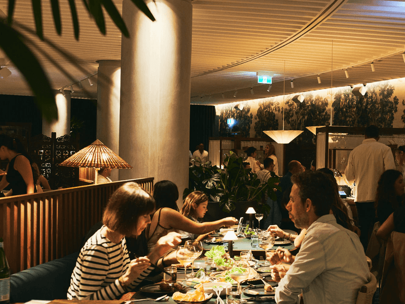 A group of people dining at a restaurant with a tropical theme and unique ceiling design.
