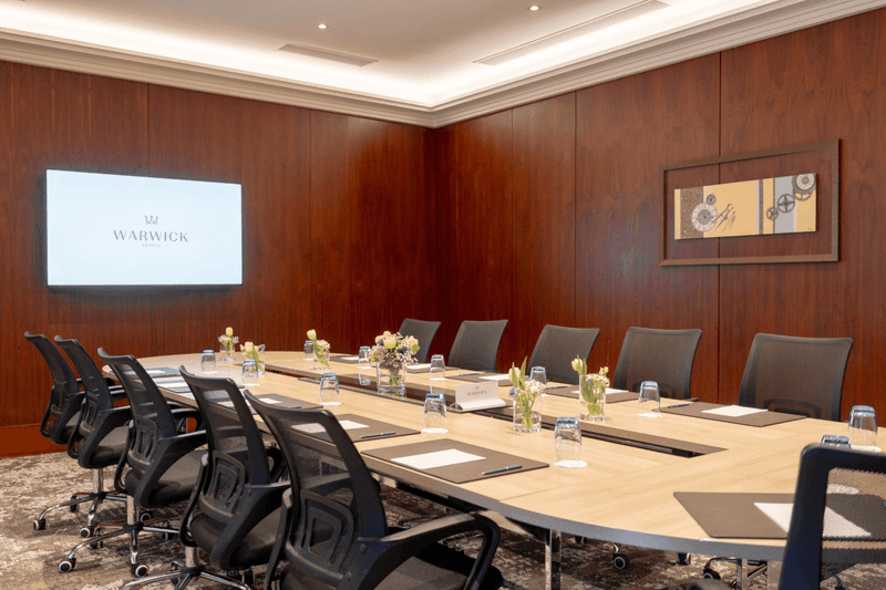 Long wooden table with chairs facing project screen in Gobelin at Warwick Geneva