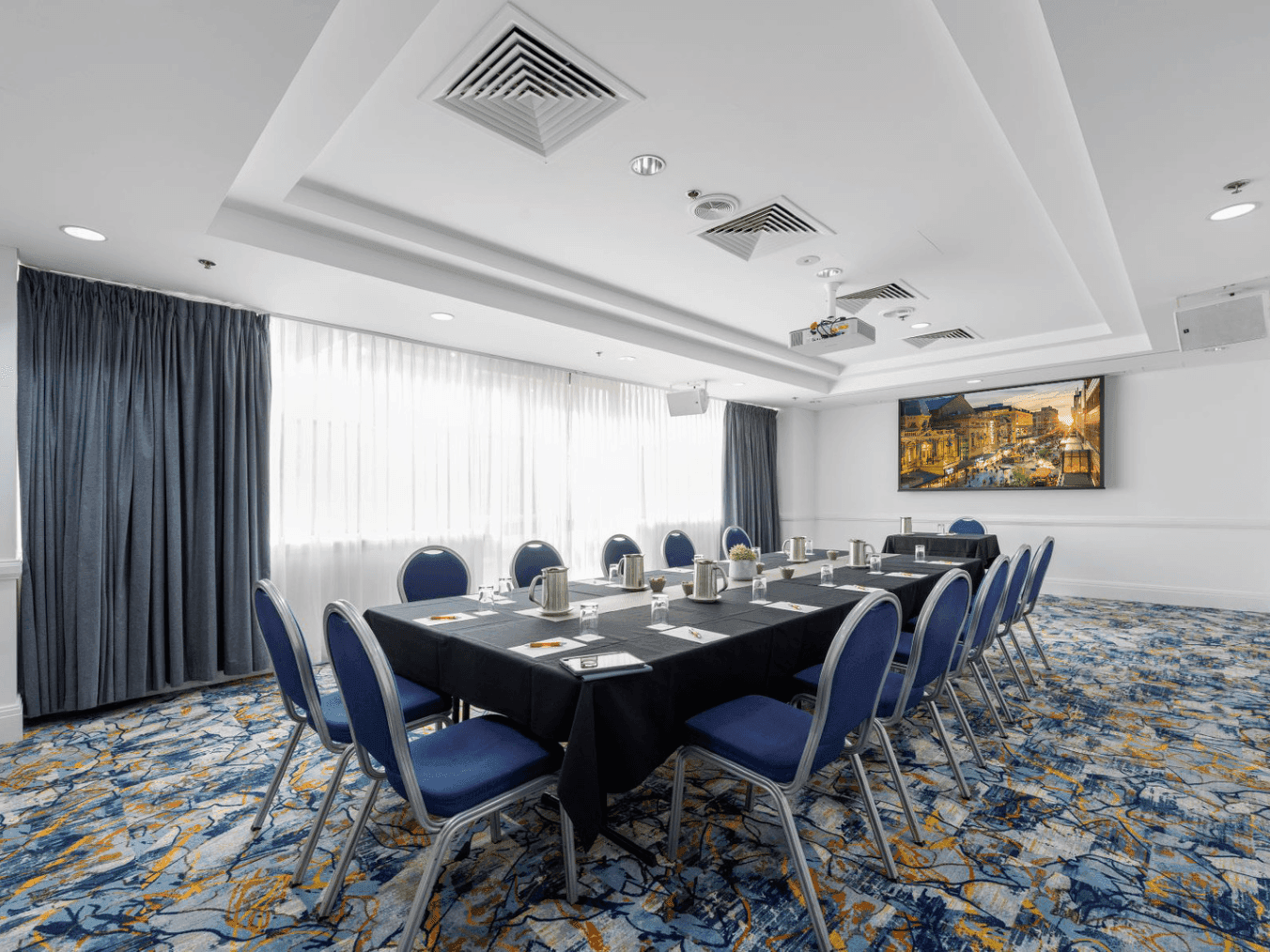 Conference table with blue chairs and modern decor in Torrens Rooms at Hotel Grand Chancellor Adelaide.