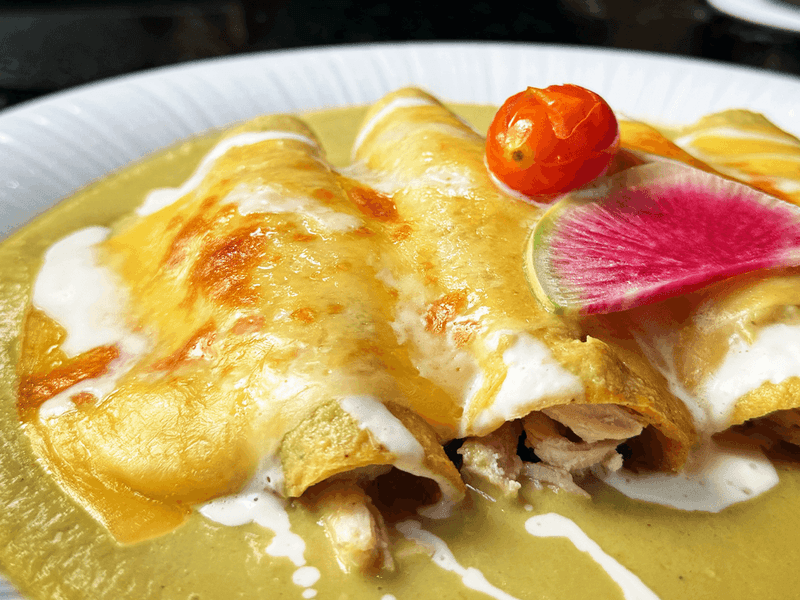 Close-up of enchiladas smothered in sauce, topped with melted cheese at Los Canarios, Fiesta Americana Travelty