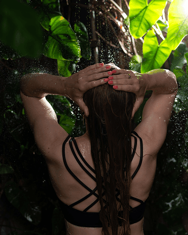 Woman enjoying an outdoor shower amidst lush tropical greenery at Morgan’s Rock Reserve & Ecolodge