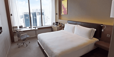 Work desk and nightstand by the bed in Skyline Room with a city view at One Farrer Hotel
