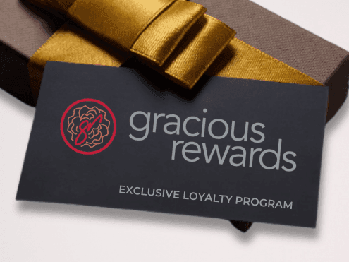 Black loyalty program card with gold ribbon on gift box displaying exclusive rewards membership benefits