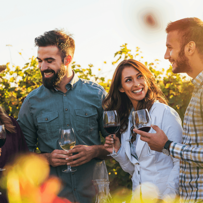 Group of friends standing in a winery with wine glasses in hand