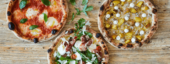 Three gourmet pizzas with toppings like prosciutto and mozzarella at Pizzaperta Manfredi in Novotel Sydney