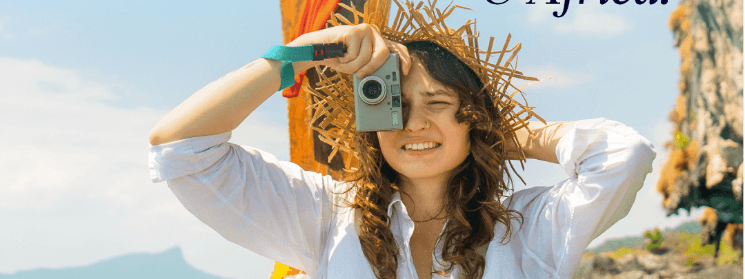 Woman in white shirt and straw hat holding camera on wooden boat with turquoise water for Accor End of Year Sale.