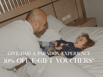 Father and child sharing a playful moment on a bed, promoting a 10% off e-gift voucher for Father's Day.