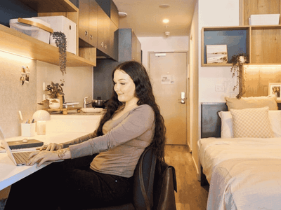 Woman working at a desk in a UniLodge Royal Melbourne room.