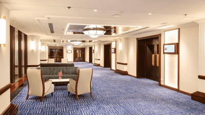 Elegant pre function space with blue carpet, chairs, couch, and decorative lights at The Grace Sydney