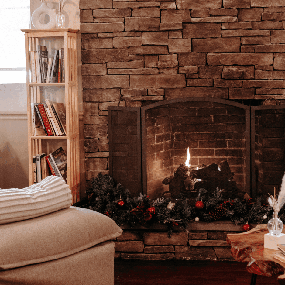 Wooden bookshelf beside a stone fireplace decorated with garland and ornaments near a live-edge table at La Tourelle Inn