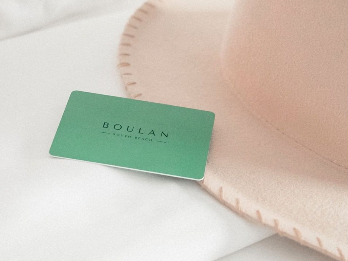 Room key & hat on a bed at Boulan South Beach Hotel