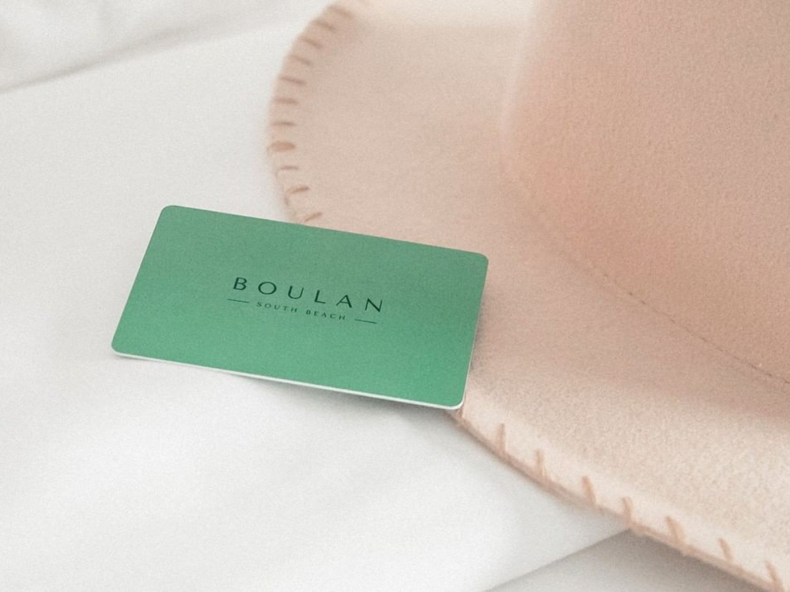 Room key & hat on bed at Boulan South Beach Hotel