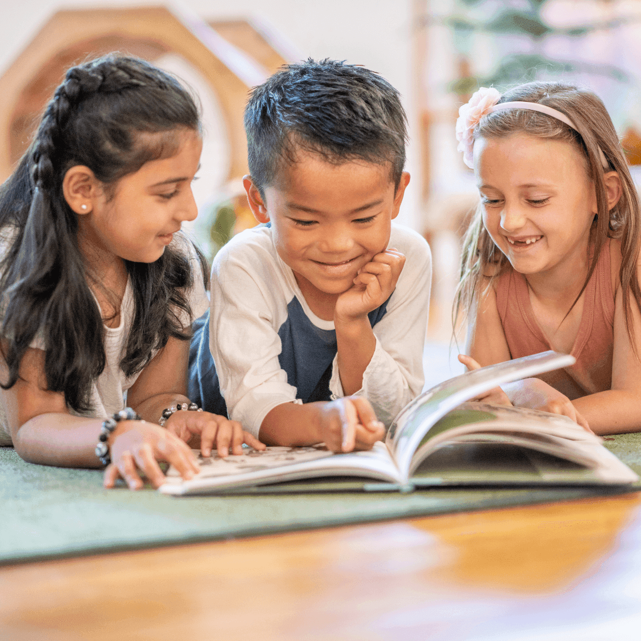 Three children reading a book together on a green rug in a cozy room at The Exeter Inn