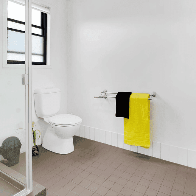 Modern bathroom with white walls, glass shower, toilet, wall-mounted sink, and bright yellow towel at Springfield Central.