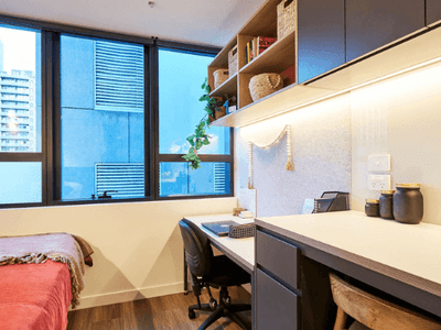 Modern room with bed, desk, chair, window, and built-in shelving with decorative items.