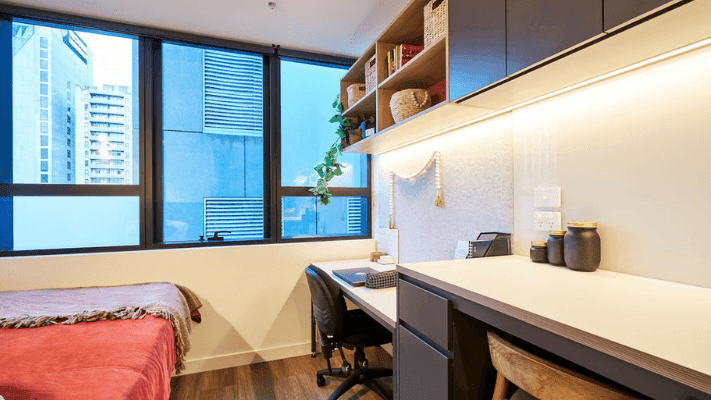 Modern room with bed, desk, chair, window, and built-in shelving with decorative items.