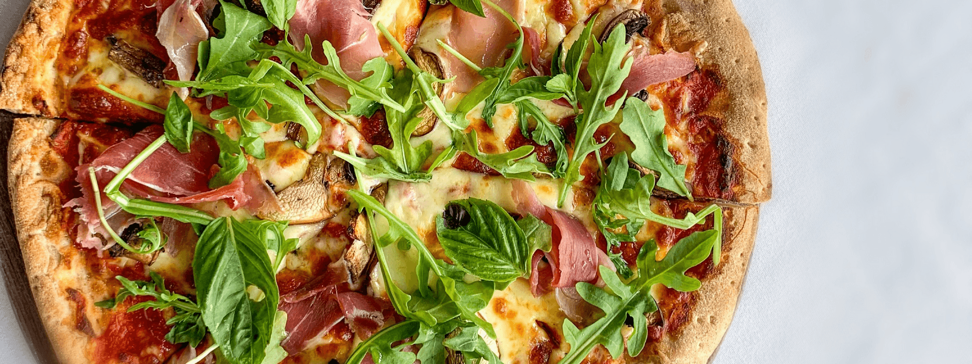 A delicious pizza topped with prosciutto and fresh arugula served in Sola Bar & Restaurant at Novotel Sunshine Coast Resort