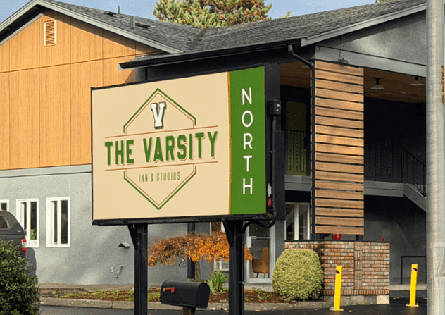 Hotel entrance with The Varsity North sign, surrounded by green grass and bushes, one of the luxury Centralia, WA hotels