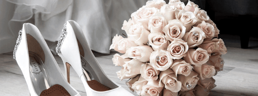 White bridal heels with a bouquet of light pink roses in Crystal Hall at Naviti by Warwick Al Khobar