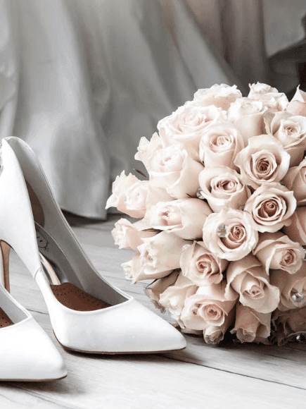 White bridal heels with a bouquet of light pink roses in Crystal Hall at Naviti by Warwick Al Khobar