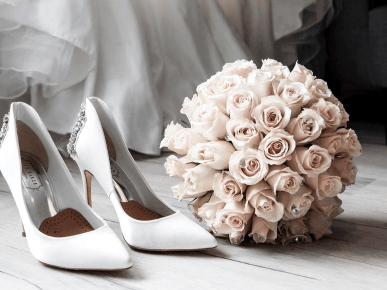 White bridal heels with a bouquet of light pink roses in Crystal Hall at Naviti by Warwick Al Khobar