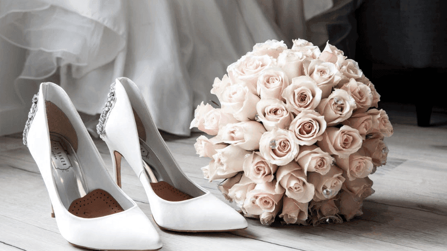 White bridal heels with a bouquet of light pink roses in Crystal Hall at Naviti by Warwick Al Khobar