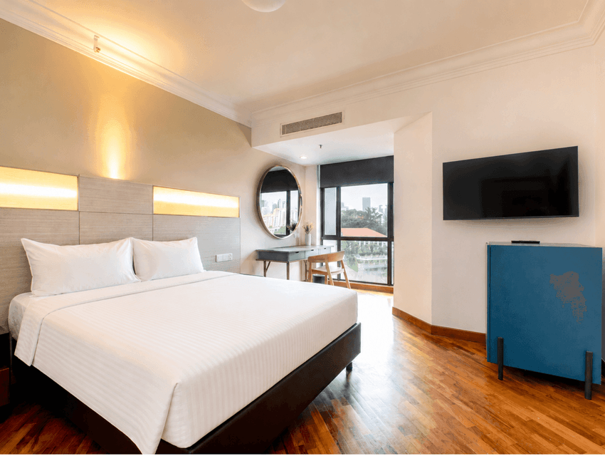Wall-mounted TV and workspace by the cozy beds in the Superior Queen Room with wooden flooring at YWCA Fort Canning