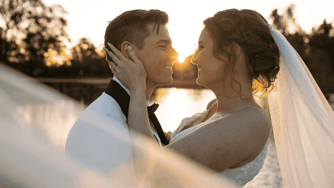 A bride and groom embracing at sunset by a lake near Mercure Kooindah Waters