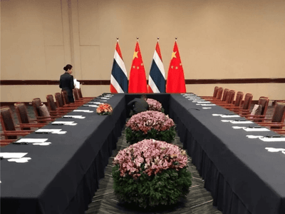 APEC 2024 conference setup featuring a long table with floral arrangements and flags at Hotel Los Delfines & Casino