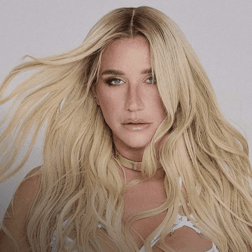 Blonde woman with long hair wearing a white top and a gold necklace.