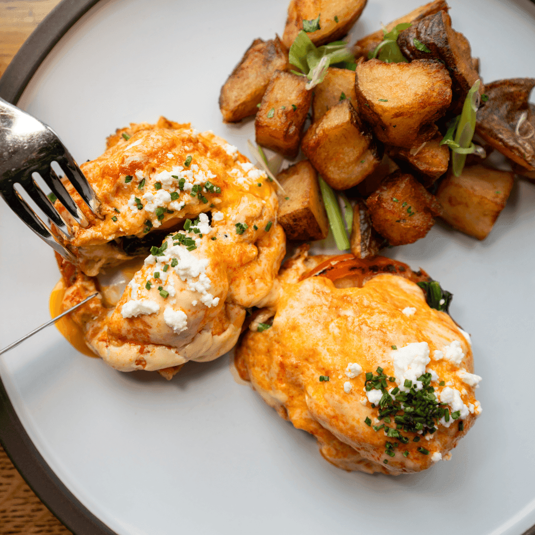 Gourmet Sunday Brunch plate with poached eggs, crumbled cheese, chives, crispy potatoes, and mushrooms.