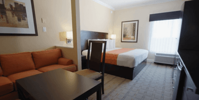 King Room with a sofa by a dark wood desk & bed at Galleria Palms Hotel, an affordable hotel near Disney World for families