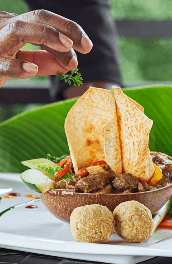 A person seasoning a tropical dish with herbs at Sun Group Hotels